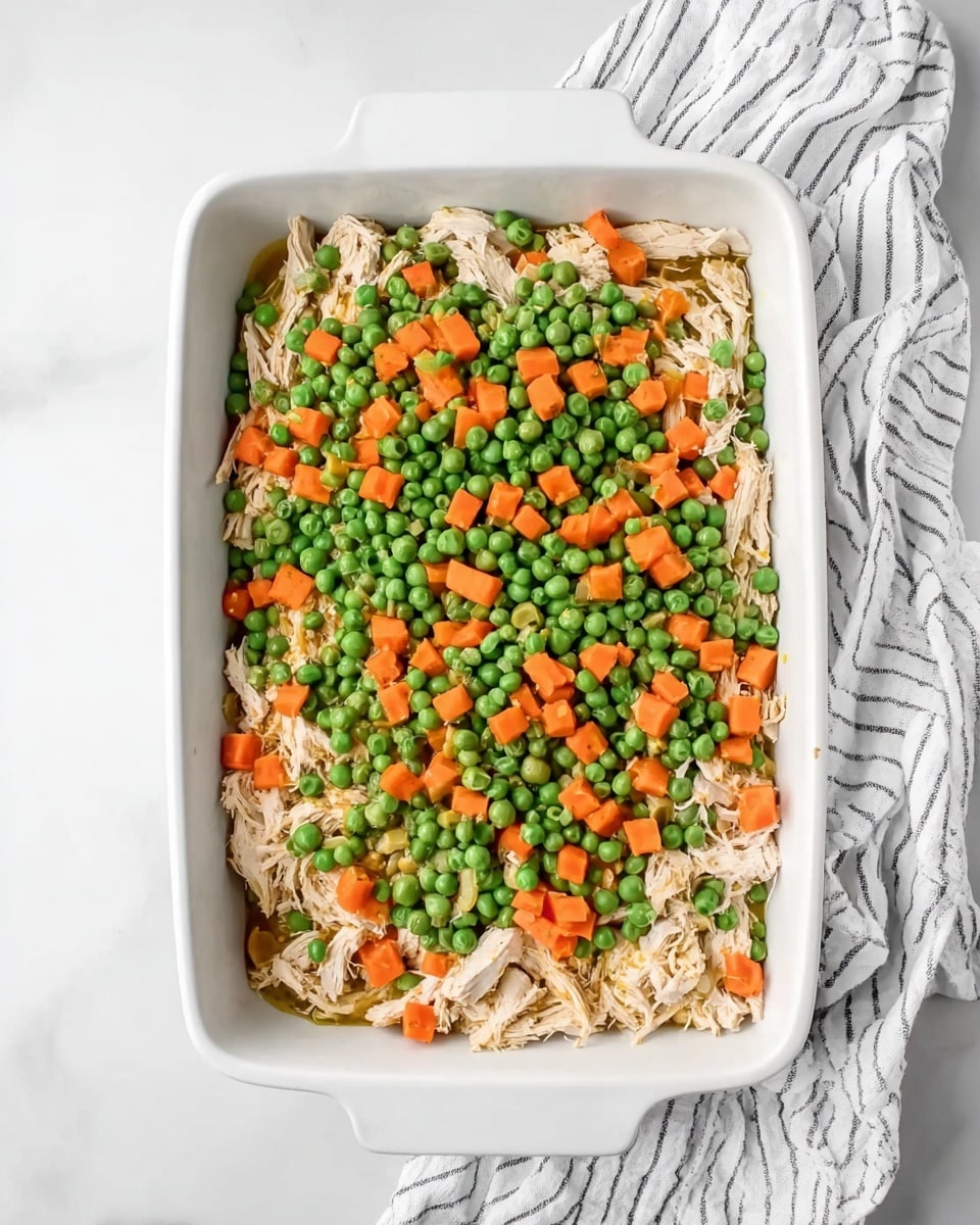 A top-down view of eight clear glass bowls arranged on a white marbled surface, each containing different cooking ingredients. In the center, a large bowl holds shredded light brown cooked chicken. Surrounding it are smaller bowls: one with bright yellow melted butter, one with white flour, one filled with mixed frozen green peas and orange carrot cubes, and another with bright orange shredded cheese. One bowl contains light beige and dark spices, another has a pale yellow liquid, a glass measuring cup has white milk, and a small open can holds smooth, pale mustard-like sauce. The bowls show a clear view of textures and colors, with the white marbled background enhancing the ingredients’ appearance, photo taken with an iphone --ar 4:5 --v 7