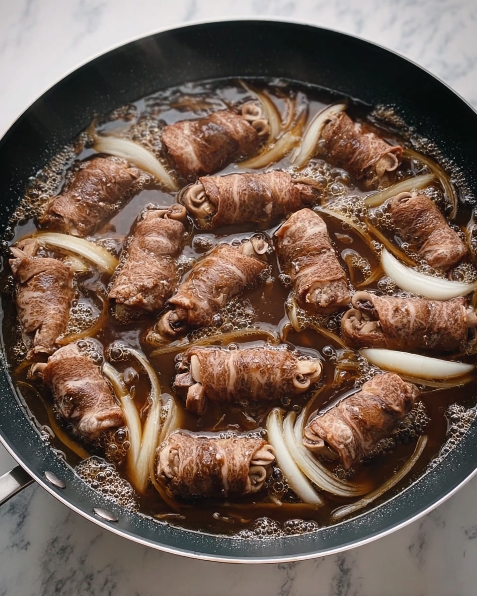 The image shows a black pan with a textured surface, placed on a white marbled texture. Inside the pan, there are 12 rolls of thin brown meat wrapped around clusters of light beige mushrooms, arranged in a circular pattern. The pan also contains sliced white onions floating in a dark brown simmering liquid broth, creating bubbles and steam rising from the surface. photo taken with an iphone --ar 4:5 --v 7