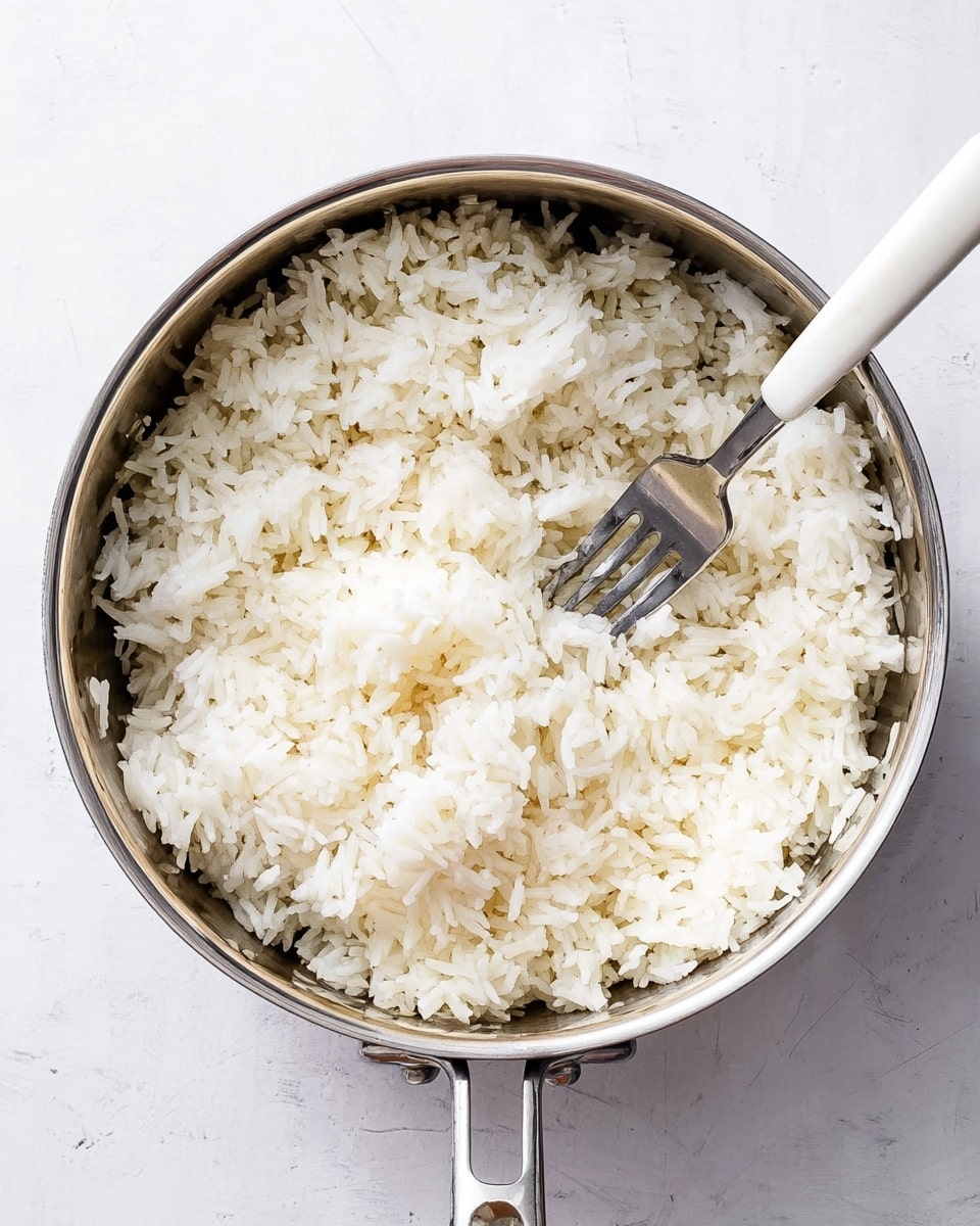 A white textured bowl filled with a single layer of fluffy white rice with small scattered slices of green onion on top, a wooden spoon resting inside the rice near the center, and a small white bowl with green onion slices placed above the main bowl on a white marbled surface; a striped beige and white cloth is partly visible in the top right corner and a wooden cutting board with fresh ginger and green onion is in the lower left corner, photo taken with an iphone --ar 4:5 --v 7