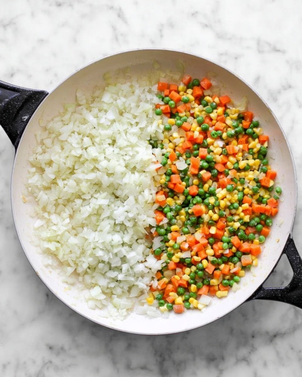 A white skillet filled with finely chopped white onions that cover the entire bottom surface, showing a slightly glossy texture from cooking. Next to it, the same white skillet is filled with a colorful mix of diced orange carrots, bright green peas, yellow corn kernels, and the softened white onions, all evenly distributed over the skillet's surface. The background is a white marbled texture. photo taken with an iphone --ar 4:5 --v 7