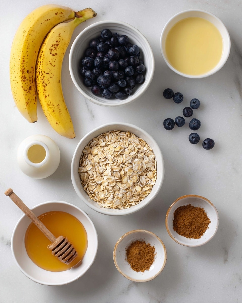 The image shows a top view of several small white bowls and items arranged on a white marbled surface. Starting from the top left, there are two yellow bananas with some dark spots. Below them, a white bowl filled with a light yellow liquid that looks smooth. To the right, a white bowl full of shiny dark blue blueberries, with a few blueberries spilled out next to it. Below that, a white ceramic jar with a cream-colored liquid inside. Centrally placed is another white bowl filled with light brown rolled oats with a few oats scattered nearby. At the bottom left is a white bowl of golden honey with a wooden honey dipper resting inside, and on the bottom right, a small white bowl containing a brown powder, likely cinnamon. The overall colors mix yellow, blue, brown, and white textures. Photo taken with an iphone --ar 4:5 --v 7