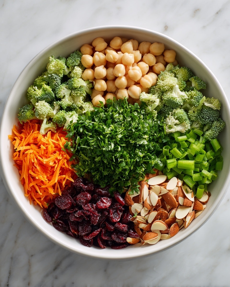 A white bowl on a white marbled surface holds seven separate layers of fresh ingredients, arranged in a neat circular pattern. Starting from the top left and moving clockwise, the layers include light beige chickpeas with a smooth texture, small dark green broccoli florets, thin light brown almond slices, bright orange shredded carrots, bright green chopped green onions, dark red dried cranberries, and a large pile of chopped fresh green parsley in the center. Each layer is clearly visible with strong colors and distinct textures. photo taken with an iphone --ar 4:5 --v 7