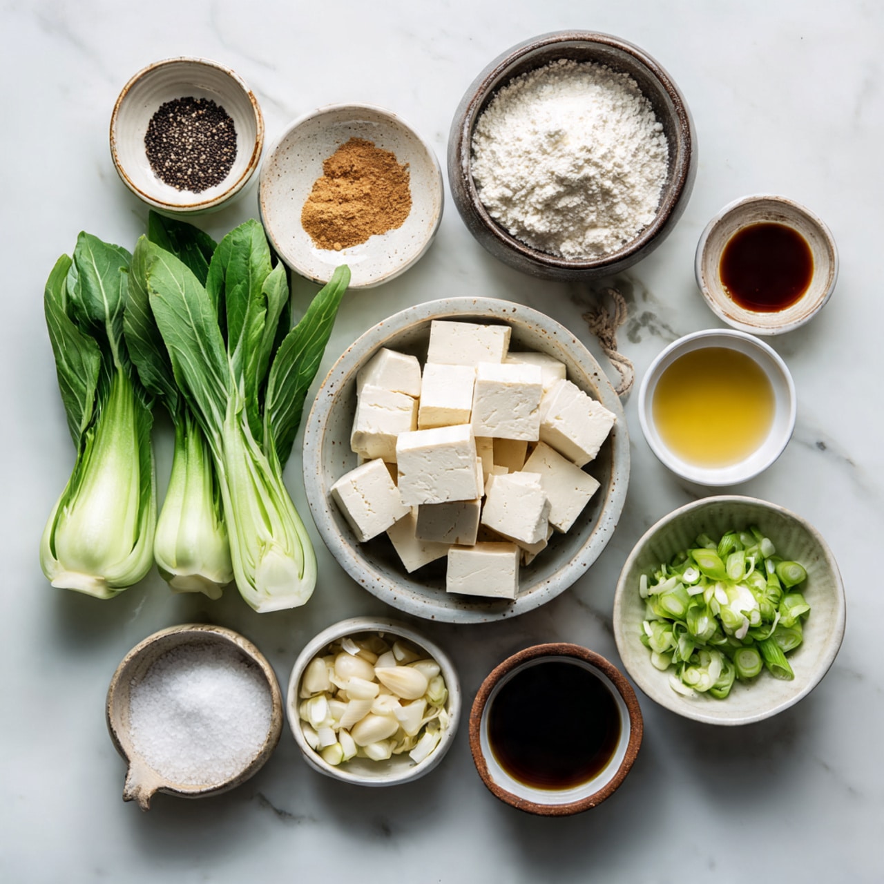 A dark bowl filled with a mix of green cooked bok choy with light green tips and browned crispy cubes of fried tofu stacked in the middle; the tofu pieces have a slightly rough texture with a few fine red strips on top; a pair of wooden chopsticks held by a woman's hand reaches into the bowl from the upper right side; the bowl is placed on a white marbled surface with a white textured cloth nearby. photo taken with an iphone --ar 4:5 --v 7
