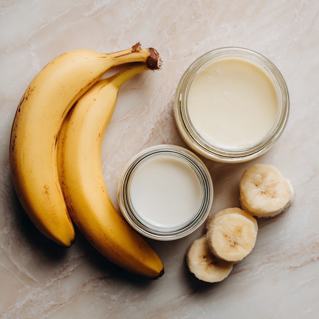 The image shows a top view of a clear blender on a white marbled surface in two stages. In the first stage, there are three pale yellow banana pieces sitting in a small amount of liquid at the bottom of the blender. The blender blades are visible underneath the ingredients. In the second stage, the banana pieces and liquid have turned into a light creamy foam filling most of the blender's container with small bubbles on top. The blender has a black handle on the right side in both views. Photo taken with an iphone --ar 4:5 --v 7