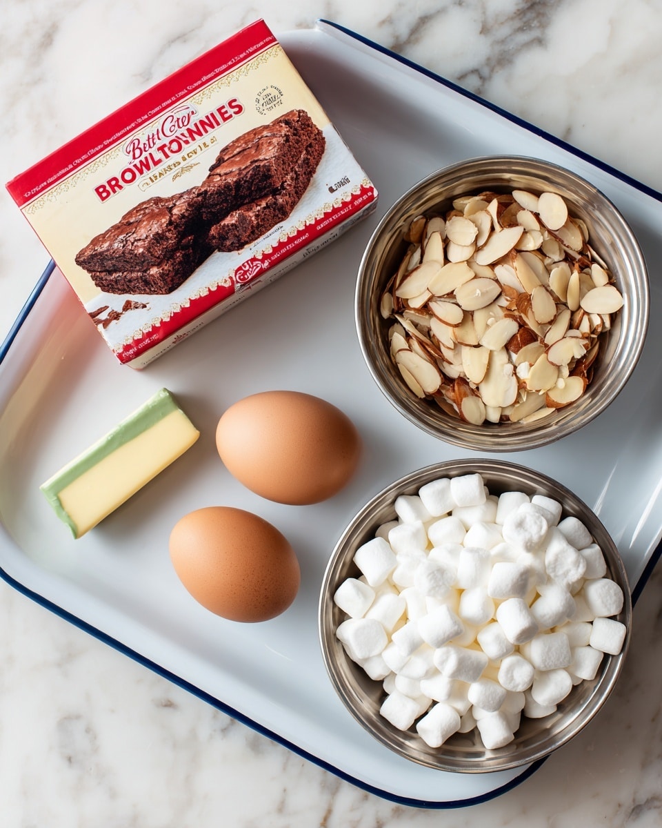 The image shows a white rectangular tray with a blue rim holding two brown eggs and a small wrapped stick of green butter, placed on a white marbled surface. Above and below the tray, two silver metal bowls are placed; the top bowl is filled with sliced almonds showing a mix of light beige and brown colors, while the bottom bowl is full of small white marshmallows. To the left of these items is a red and white box of Betty Crocker Gluten Free Chocolate Brownies mix with an image of two chocolate brownies on it, set directly on the white marbled surface. photo taken with an iphone --ar 4:5 --v 7