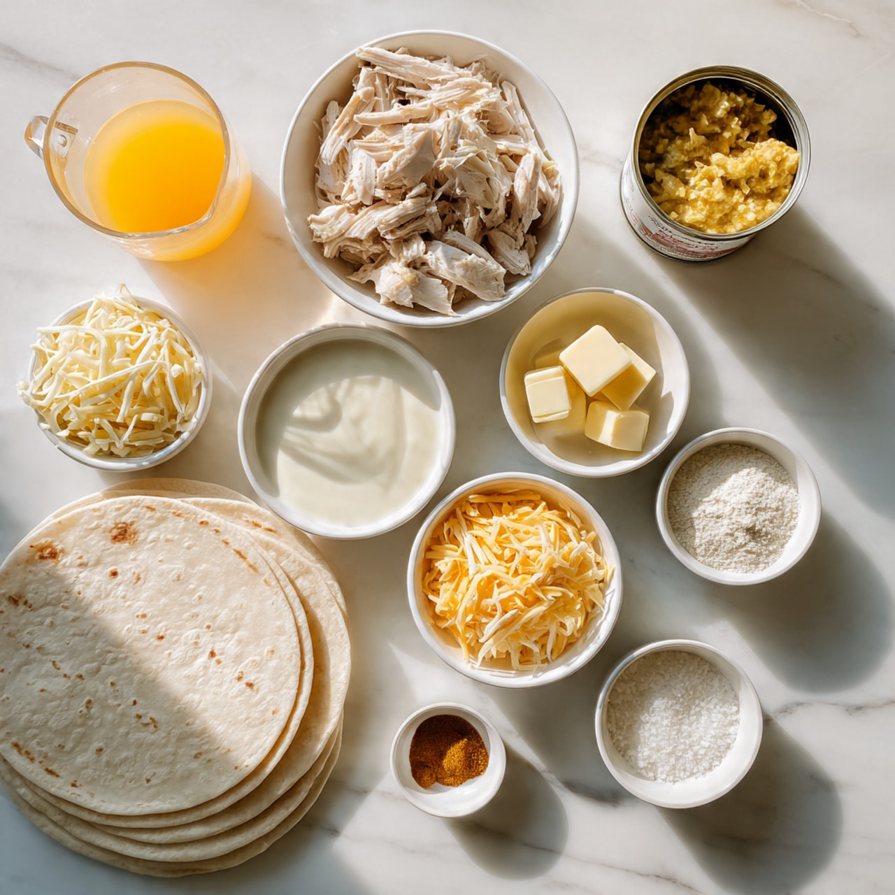 The image shows several small white bowls and a glass measuring cup arranged on a white marbled surface. One bowl contains shredded light beige chicken, another has a mix of shredded yellow and white cheese, and a third bowl holds a smooth, white creamy sauce. There is a small bowl with a few cubes of pale yellow butter and another small bowl with white flour. Two small dishes hold various light brown and off-white powdered spices. A stack of white tortillas rests flat on the surface near the bottom left. The glass measuring cup holds a light orange-yellow liquid. A small open can with a chunky yellow contents is near the top right. photo taken with an iphone --ar 4:5 --v 7