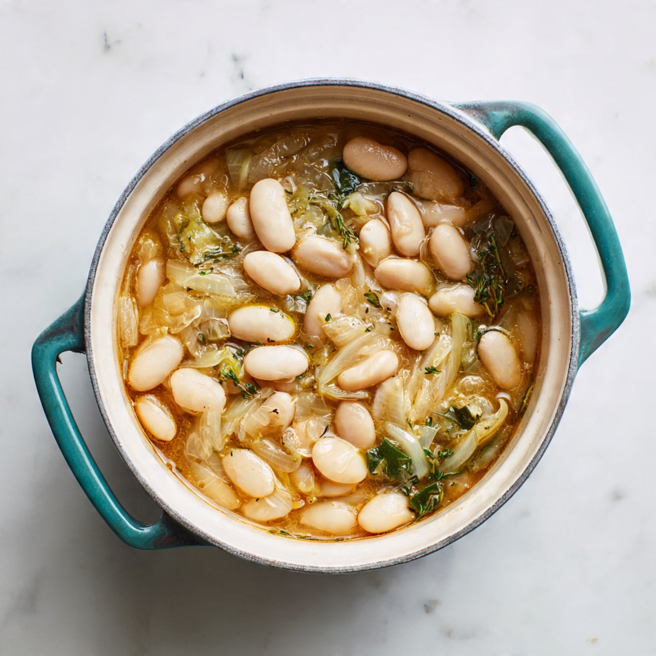 A white round pot with teal handles filled with a mixture of large white beans, light green chopped vegetables, and thinly sliced translucent onions in a light brown broth. The beans sit on the top layer, evenly spread out, with the vegetables and onions underneath, all covered with the broth that gives a slightly shiny surface. The pot is placed on a white marbled surface. photo taken with an iphone --ar 4:5 --v 7