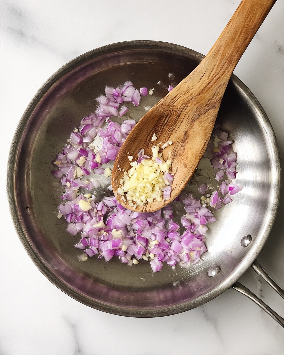 A metal pan with a shiny surface is shown from above, containing small pieces of diced purple onions and minced light yellow garlic spread around. A wooden spoon with a natural grain texture is resting inside the pan, stirring a little bit of the onions and garlic. The pan and spoon are placed on a white marbled surface. Photo taken with an iphone --ar 4:5 --v 7