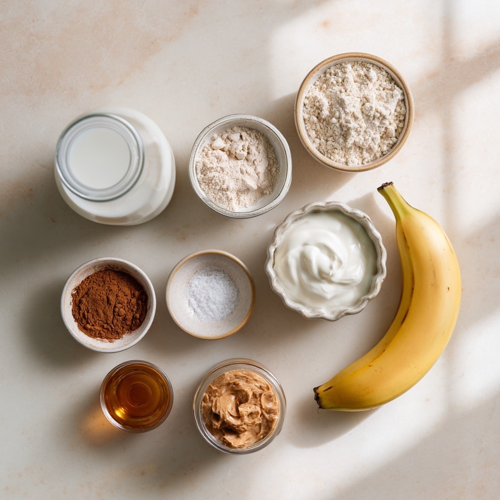 A clear blender container viewed from above shows three layers: the bottom layer is a white liquid, the middle layer consists of light beige powder mostly covering the liquid, and near the left edge there is a small area of reddish-brown powder. The textures of the powders look fine and soft, resting unevenly on the liquid layer below. The background features a white marbled texture with a hint of a golden-brown and tan chair or structure blurred underneath. photo taken with an iphone --ar 4:5 --v 7