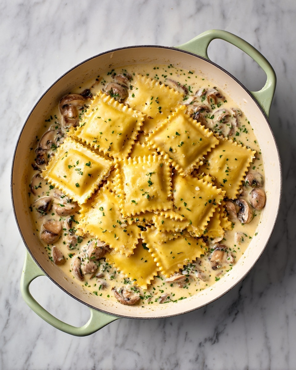 A white pan with light green handles holds a creamy sauce mixed with small mushroom slices and herbs, forming the first layer at the bottom. On top of this sauce, there is a second layer of yellow square ravioli pasta with crimped edges, stacked unevenly and covering most of the sauce beneath. The pan is placed on a white marbled background. photo taken with an iphone --ar 4:5 --v 7
