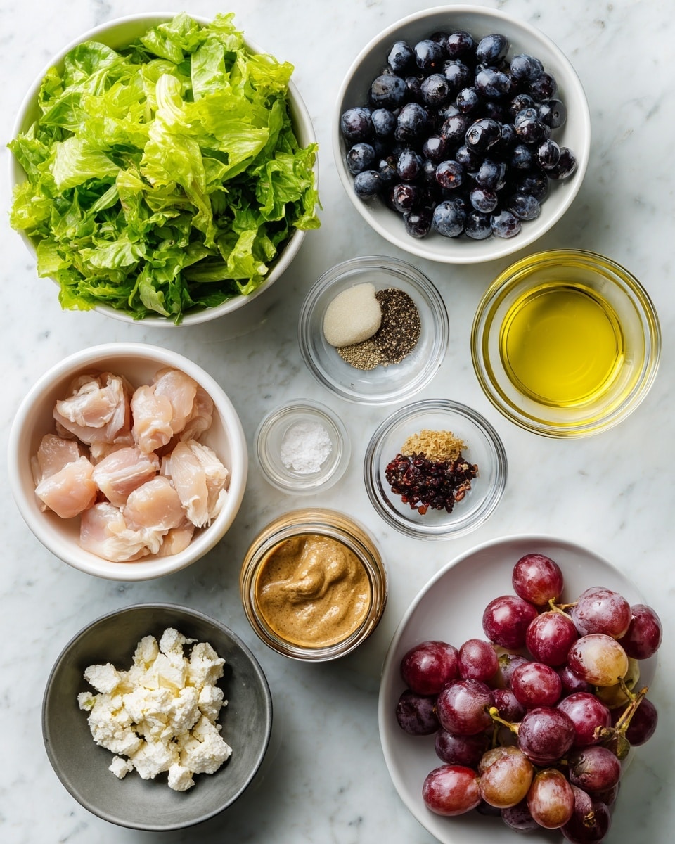 A white bowl placed on a white marbled surface, filled with five distinct layers: bright green leafy lettuce on the top left, dark purple-blue blueberries on the top right, white crumbly cheese on the bottom right, roasted almond pieces and grilled chicken strips with a golden-brown color in the center, and sliced red grapes on the bottom left. All layers are drizzled with a creamy, light brown dressing. To the upper left of the bowl is a clear glass jar of the same dressing sitting on a dark blue textured cloth with some dressing spilled on the outside. A silver spoon rests on the right side inside the bowl. Photo taken with an iphone --ar 4:5 --v 7