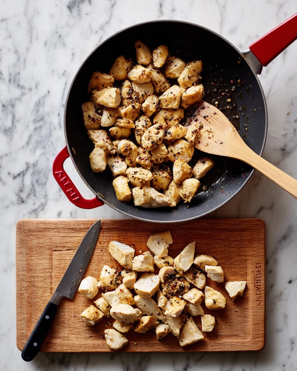 The image shows two parts: the top part has a black pan with red handles on a white marbled surface, filled with cooked, light brown pieces of chicken that have some black pepper on them, with a wooden spatula touching the chicken from the top right. The bottom part shows a white wooden cutting board with many cut pieces of the same cooked chicken scattered around; a black-handled knife lies diagonally at the top of the board, all set on the white marbled surface. Photo taken with an iphone --ar 4:5 --v 7